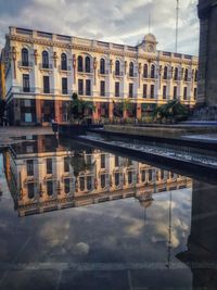 Reflection of building in puddle against sky