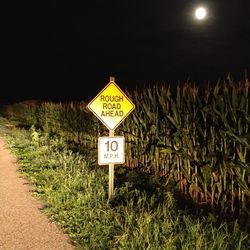 Information sign on field against sky at night