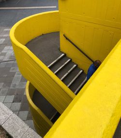 High angle view of yellow metallic railing on footpath