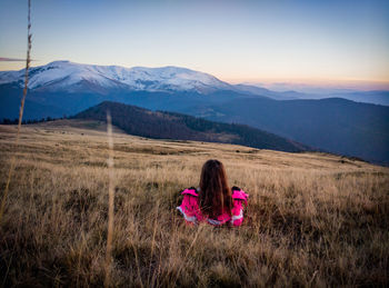 Woman relaxing on field against mountains