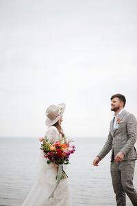 People standing on rock by sea against sky