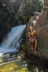 Young woman on rock in forest