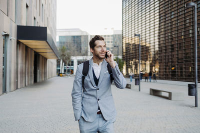 Businessman standing with hand in pocket talking on smart phone