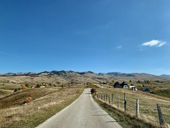 Road amidst field against sky