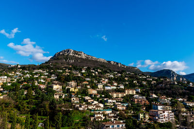 Townscape by mountain against blue sky