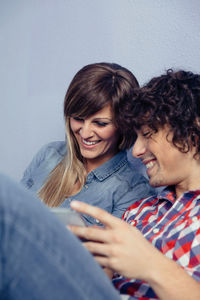 Close-up of couple using digital tablet while leaning on bed at home