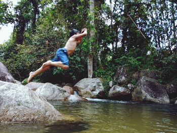 Man jumping on rock by lake