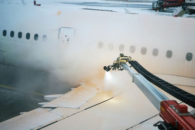 Deicing of airplane wing before take off. winter frosty night and ground service at airport.
