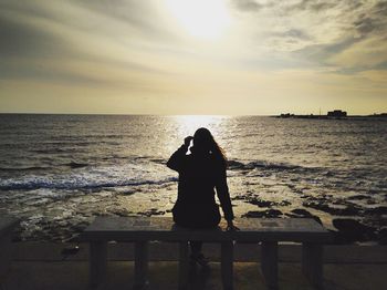 Silhouette man standing in front of sea during sunset