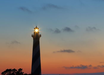 Low angle view of illuminated lighthouse against sky during sunset