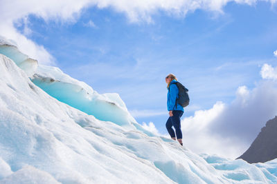 Low angle view of woman standing on snowcapped mountain