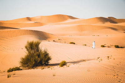 Man walking on desert against clear sky