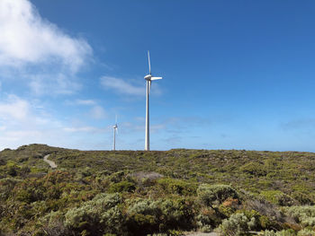 Wind turbines on field against sky