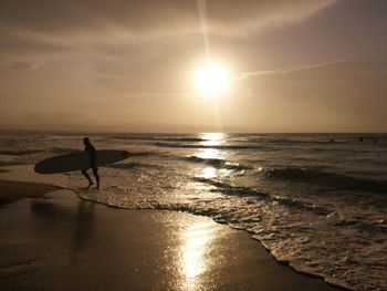 Silhouette man on beach against sky during sunset