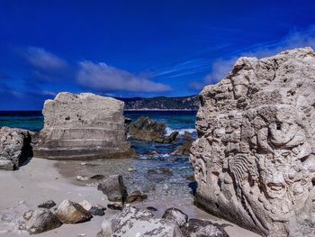 Rocks by sea against blue sky