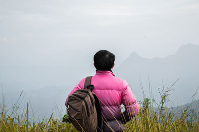 Rear view of backpack man looking at mountain against sky