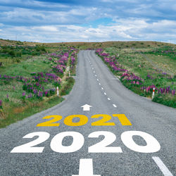 Text on road amidst grassy field against sky