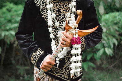 Midsection of woman holding umbrella standing on field