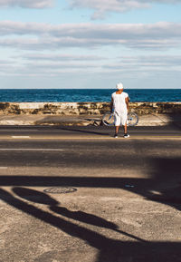 Rear view of woman on beach against sky