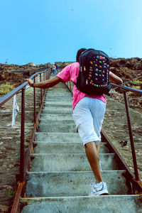 Rear view of woman standing on railing against clear sky