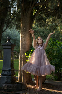 Full length of girl standing against tree