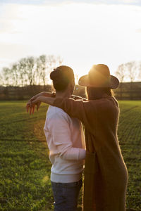 Rear view of couple standing on field against sky