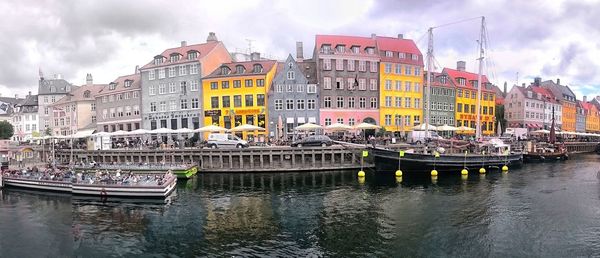 Boats moored on canal in city against sky