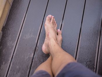 Low section of woman relaxing on wooden floor