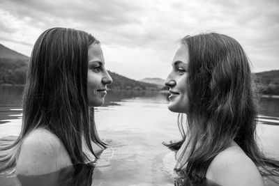 Profile view of shirtless female friends face to face in lake