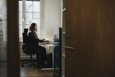 Female entrepreneur sitting on chair and working at office