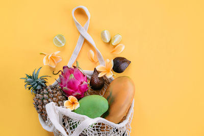 Close-up of various flowers on table against yellow background