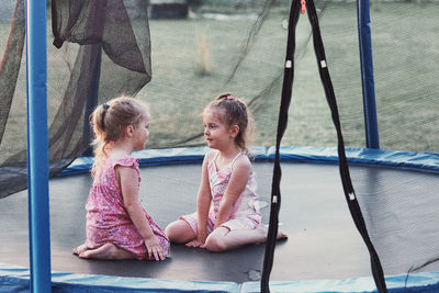 Girls sitting on trampoline seen through netting