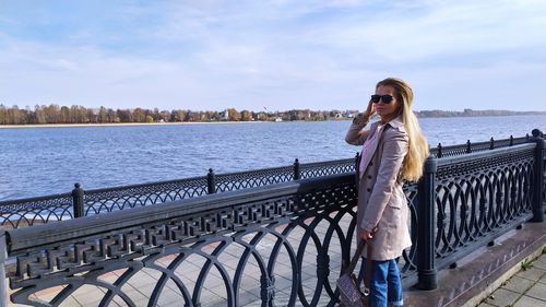 Woman standing by railing against sky