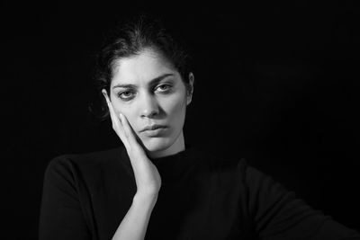 Portrait of sad woman over black background