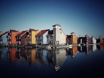 Buildings by river against blue sky