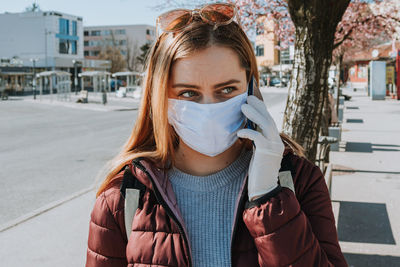 Portrait of young woman standing on street in city