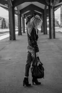 Full length of woman holding purse standing on road