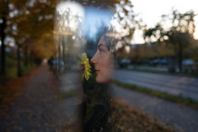 Double exposure image of woman with flower against road