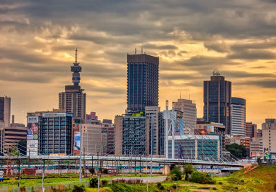 Modern buildings in city against sky during sunset