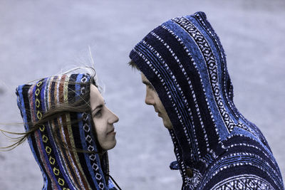 Close-up of young couple wearing patterned hooded shirts on field