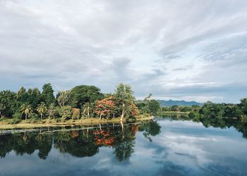 Scenic view of river with clouds reflection amidst trees