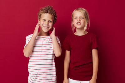 Portrait of sibling against red background