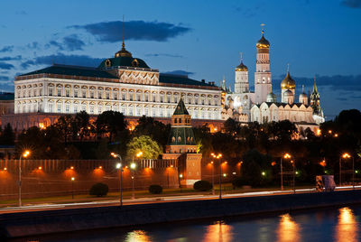 Moscow kremlin by river against sky in city at dusk