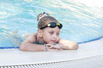 Little girl in swimming goggles swims in the pool