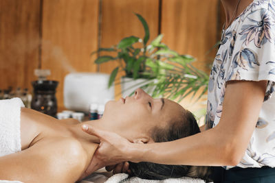 Aromatherapy massage, masseuse massaging client with therapeutic ethereal oil
