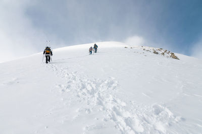 Mountaineers walking up along a snowy ridge with the skis in the backpack. skier on the climbing