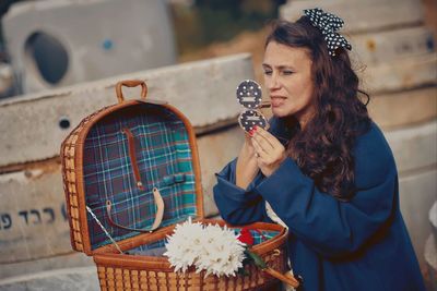 Mature woman applying make-up while standing outdoors