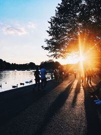 People by tree against sky during sunset