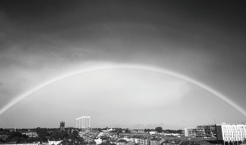 Rainbow over city against sky