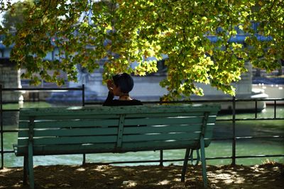 Rear view of woman sitting on bench in swimming pool